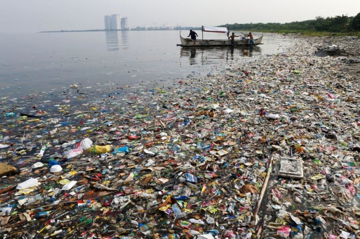 Waste accumulates in Phillipines body of water due to unregulated waste discharge as fisherman operate nearby